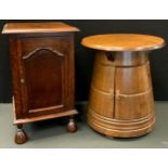 A 20th century oak drinks barrel table, circular top, tapering cabinet base with single door, 51