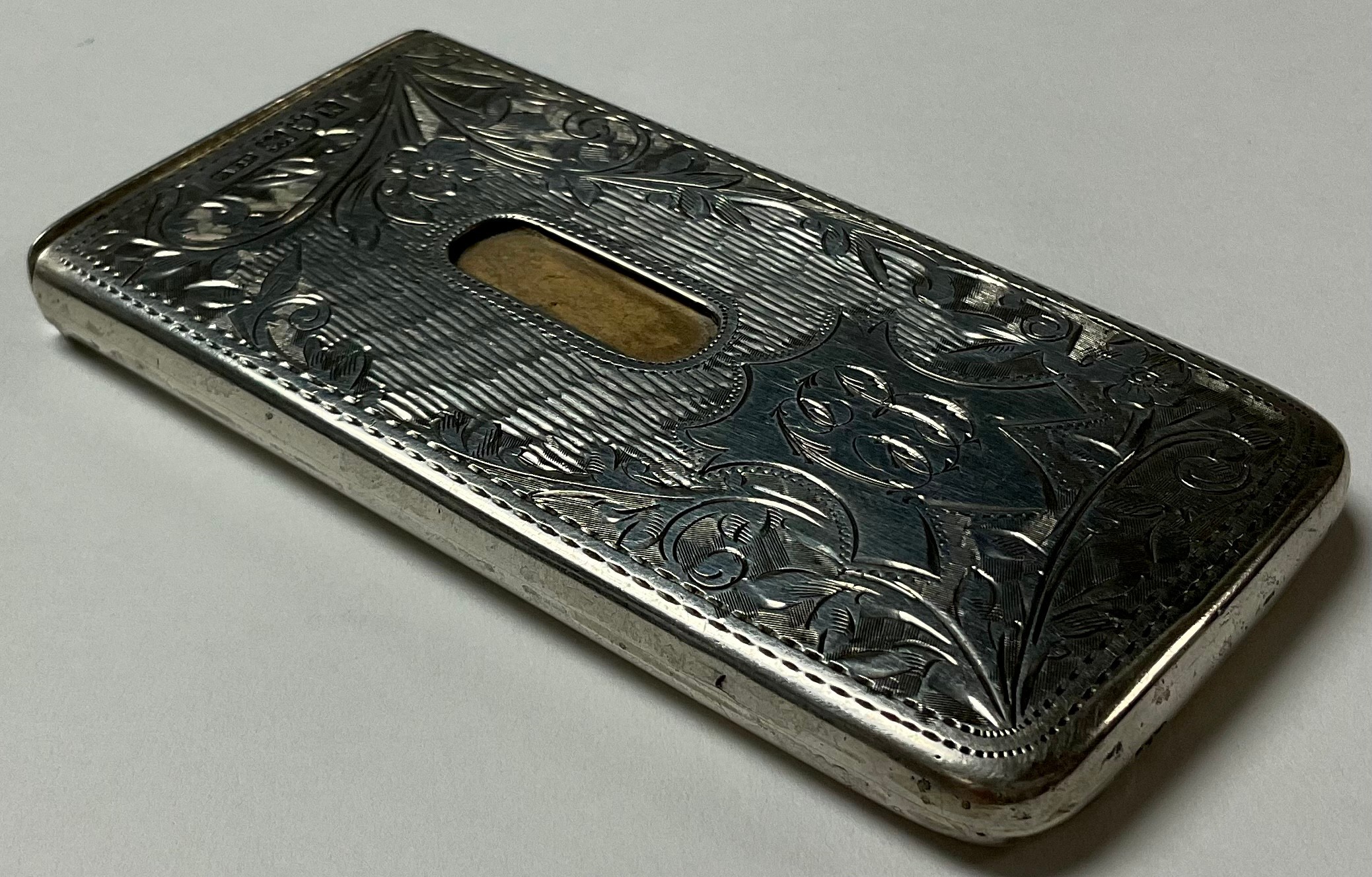 An Edward VII silver visiting card case, chased and engraved with foliate scrolls, patented silver