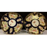 A pair of Royal Worcester cabinet plates, gilt framed panels of exotic birds and butterflies on blue