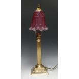A brass table lamp, fluted pillar, square base with acanthus border, cranberry-type glass shade,