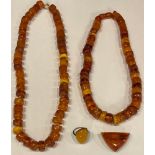 Two amber bead necklaces; a Baltic amber ring; a brooch (4)