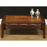 A Chinese hardwood kang or low tea table, rounded rectangular panelled top above a carved and