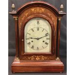An early 20th century mahogany inlaid mantel clock, arched case, Roman numerals on silvered dial,
