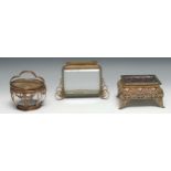 A French gilt metal circular dressing table box, shaped handle, the glazed lid set with lace and