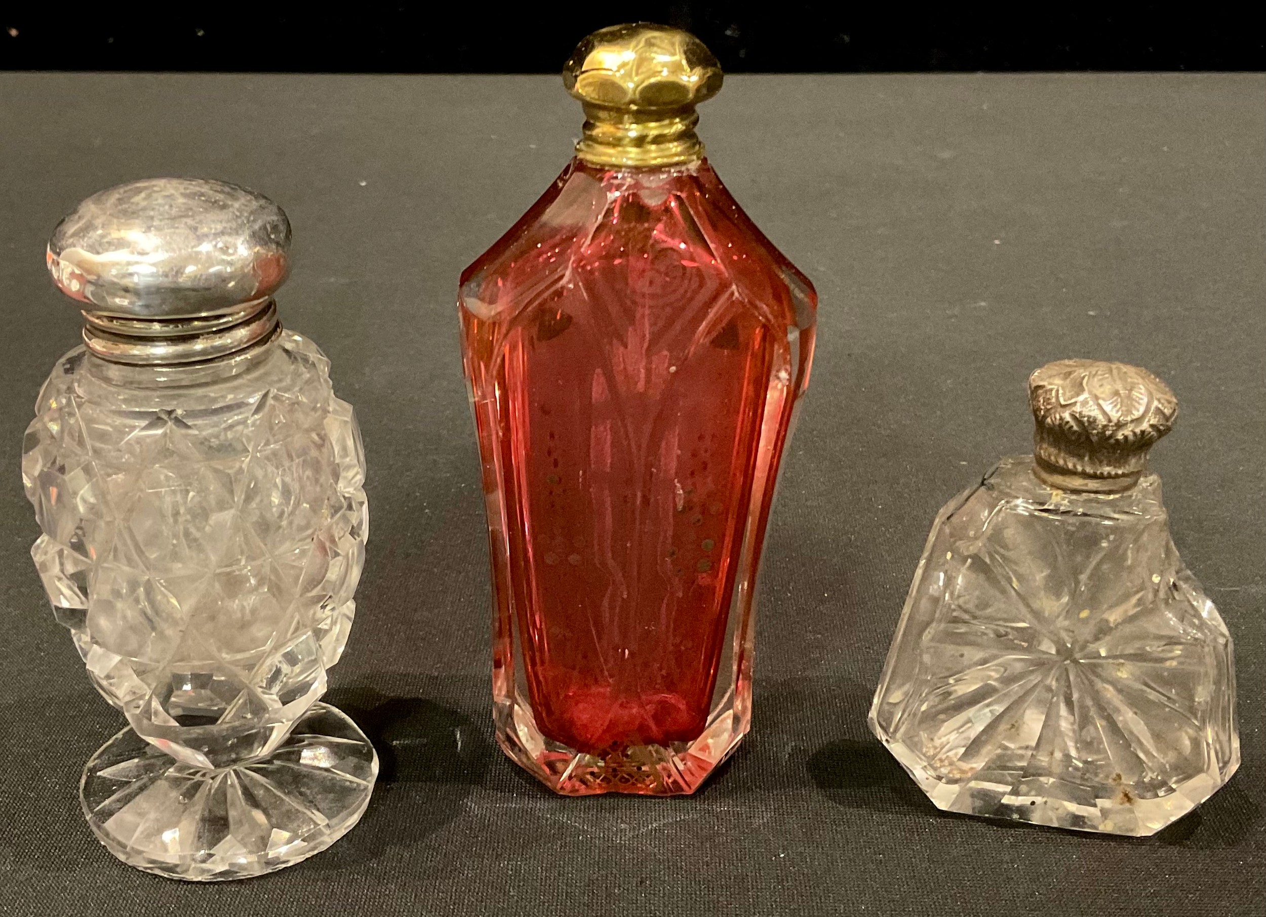 A cut glass silver topped pedestal scent bottle, Birmingham 1909; another; a ruby glass scent bottle