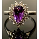 A 9ct white gold ring, the central pear cut amethyst surrounded by brilliant cut cubic zirconia,