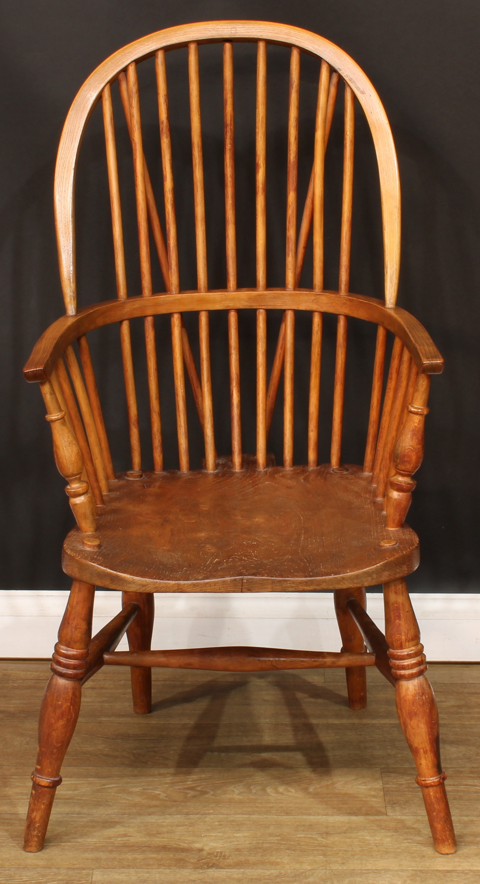 A beech and elm Windsor elbow chair, hoop back, one-piece mid-rail, turned arm posts, saddle seat,