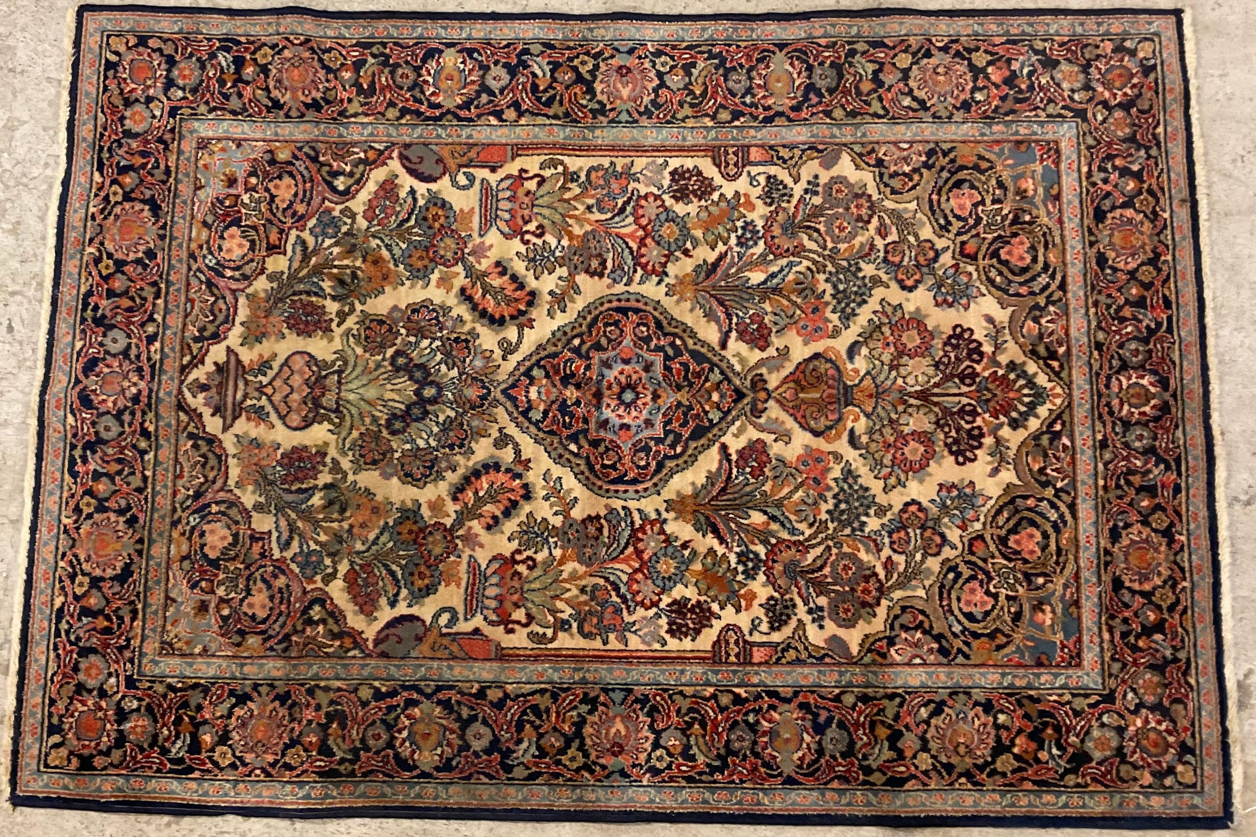 A Middle Eastern Persian woollen rectangular rug, with stylised vases of flowers in tones of red and