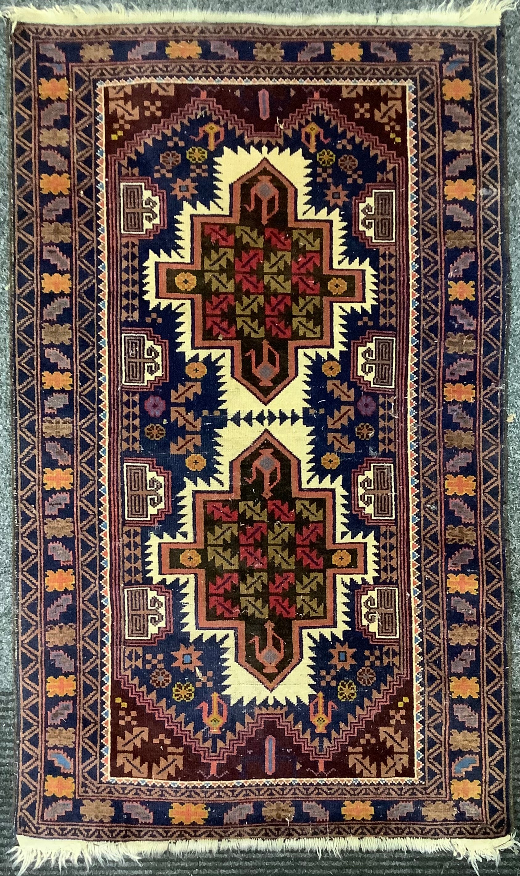 A Middle Eastern woollen rug or carpet, geometric shapes in tones of red, blue and yellow, 152cm x