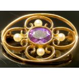 A 9ct gold oval openwork brooch, set with a single central faceted amethyst surrounded by four