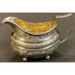 A George IV silver jug, embossed, chased and engraved with foliate scrolls, gilded interior, resting