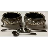 A pair of Victorian silver table salts, embossed with rosebuds, each resting on three cabriole