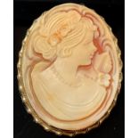 A gold coloured metal mounted shell cameo brooch, carved with a beauty