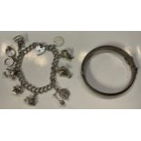 A silver charm bracelet and padlock with nine charms; a silver bangle, marked Sterling