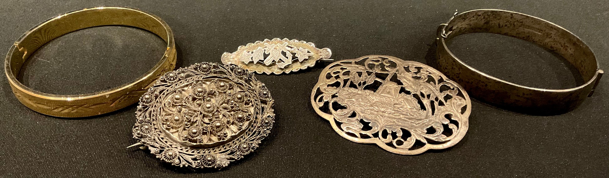 A Dutch silver brooch; a filigree silver brooch; a heart and anchor brooch; a silver bangle,