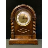 An early 20th century oak mantel clock, Arabic numerals,, the arched case with turned columns,