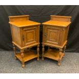 A pair of early 20th century Gillows oak bedside cabinets, oversailing top, ornate scrolled panel