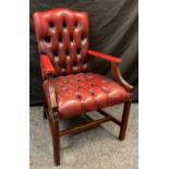 A mid 20th century button-back open arm office chair, sang de boeuf leather, mahogany arms and legs,