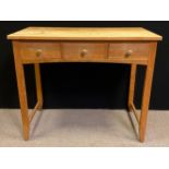 A 20th century light oak side table, over-sailing rectangular top, three short drawers to frieze,