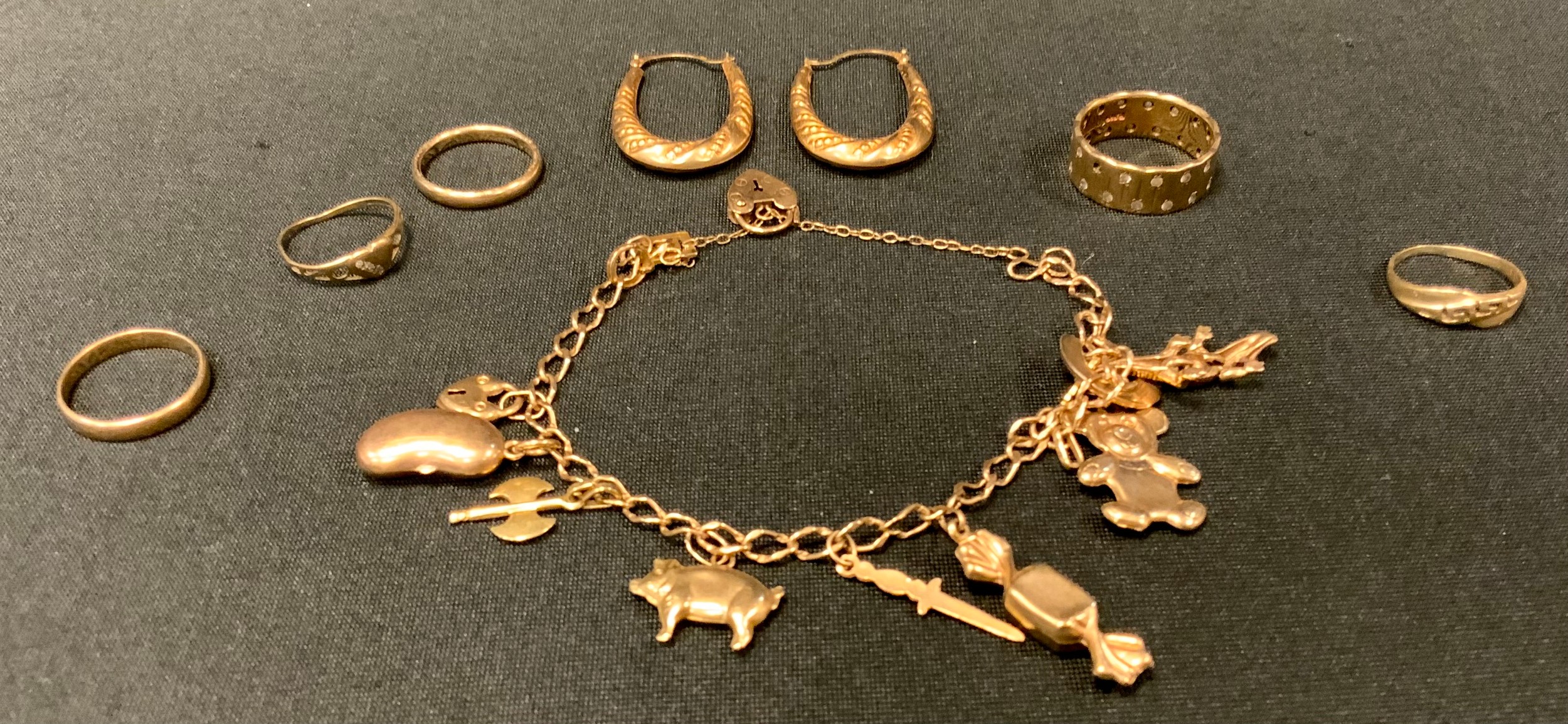 A 9ct gold charm bracelet; 9ct gold rings; another 14ct gold; pair of yellow metal hoop earrings,