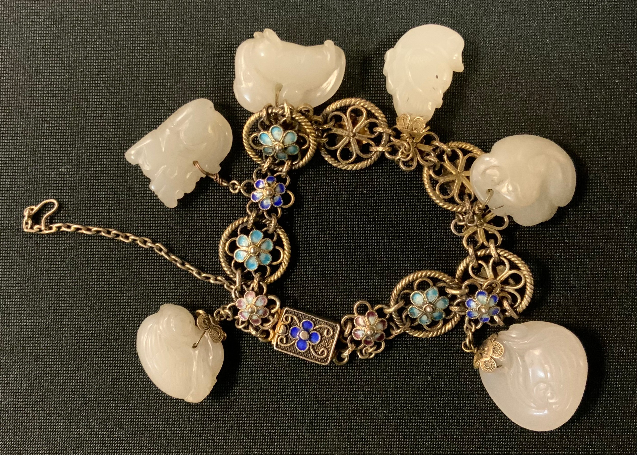 An enamelled white metal and carved stone bead bracelet, the floral link panels suspending six