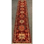 A Persian Karajeh runner carpet / rug, hand-knotted in tones of red, grey, pink, and cream, with a