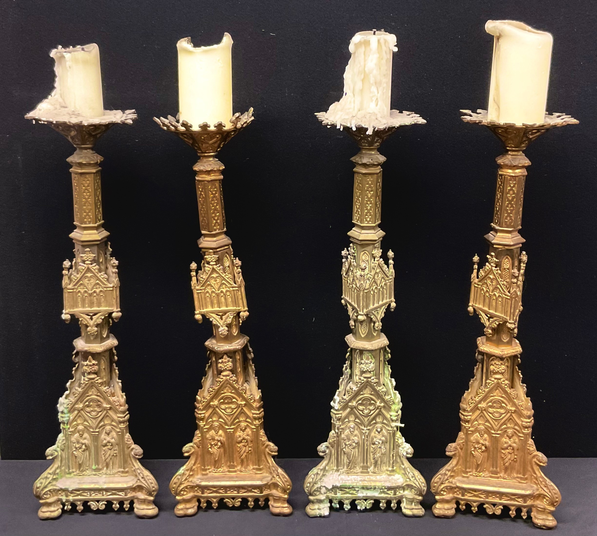 A set of four Gothic Revival gilt metal altar pricket candlesticks, cast throughout with figures and