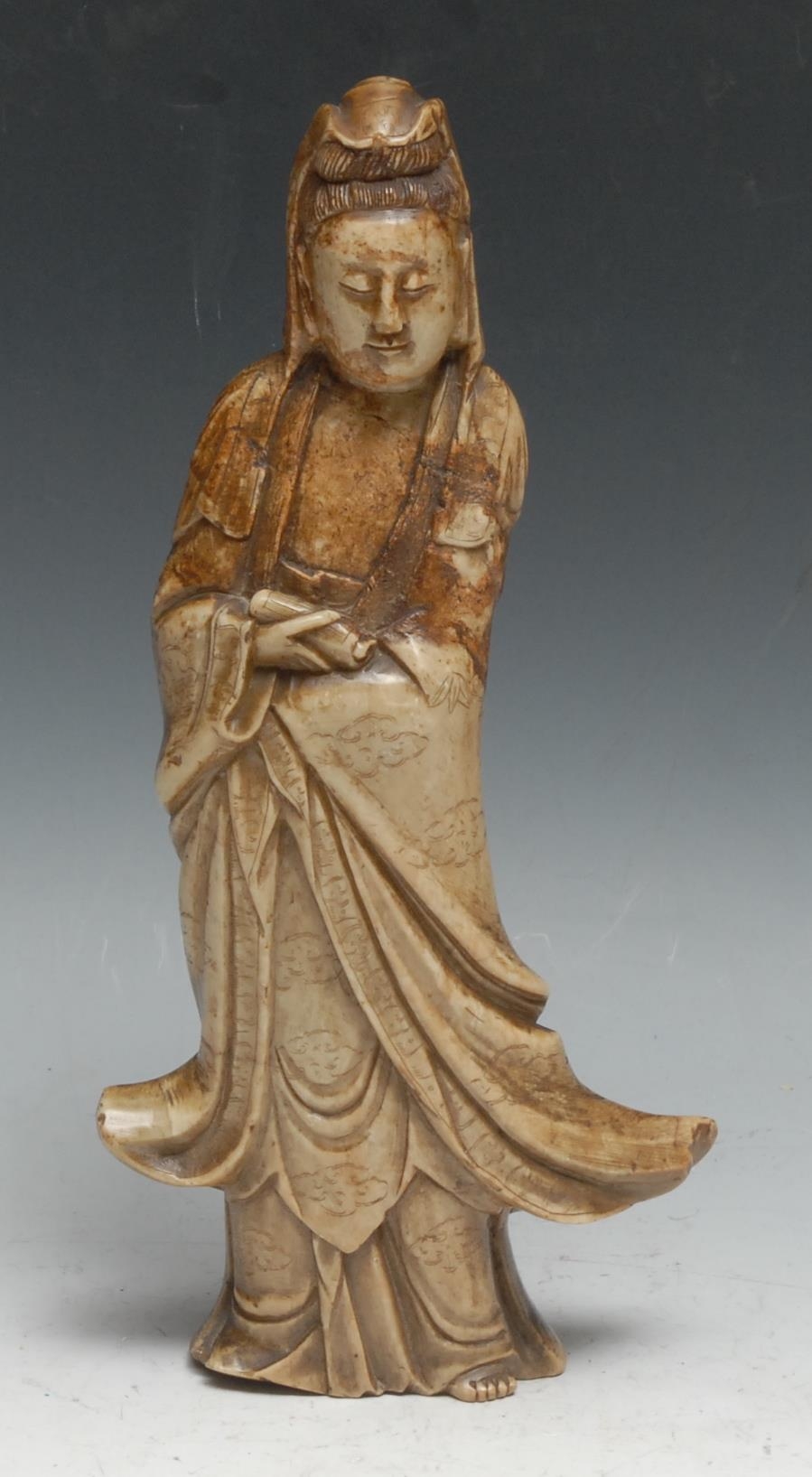 A Chinese soapstone figure, carved as Guanyin, she stands, holding a scroll, 26cm high, 19th century