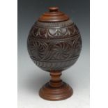 A 19th century pedestal coconut cup, carved with roundels and lunettes, turned mahogany cover and
