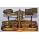 A set of early 20th century brass and walnut postal scales, serpentine base, 21cm wide, c.1920