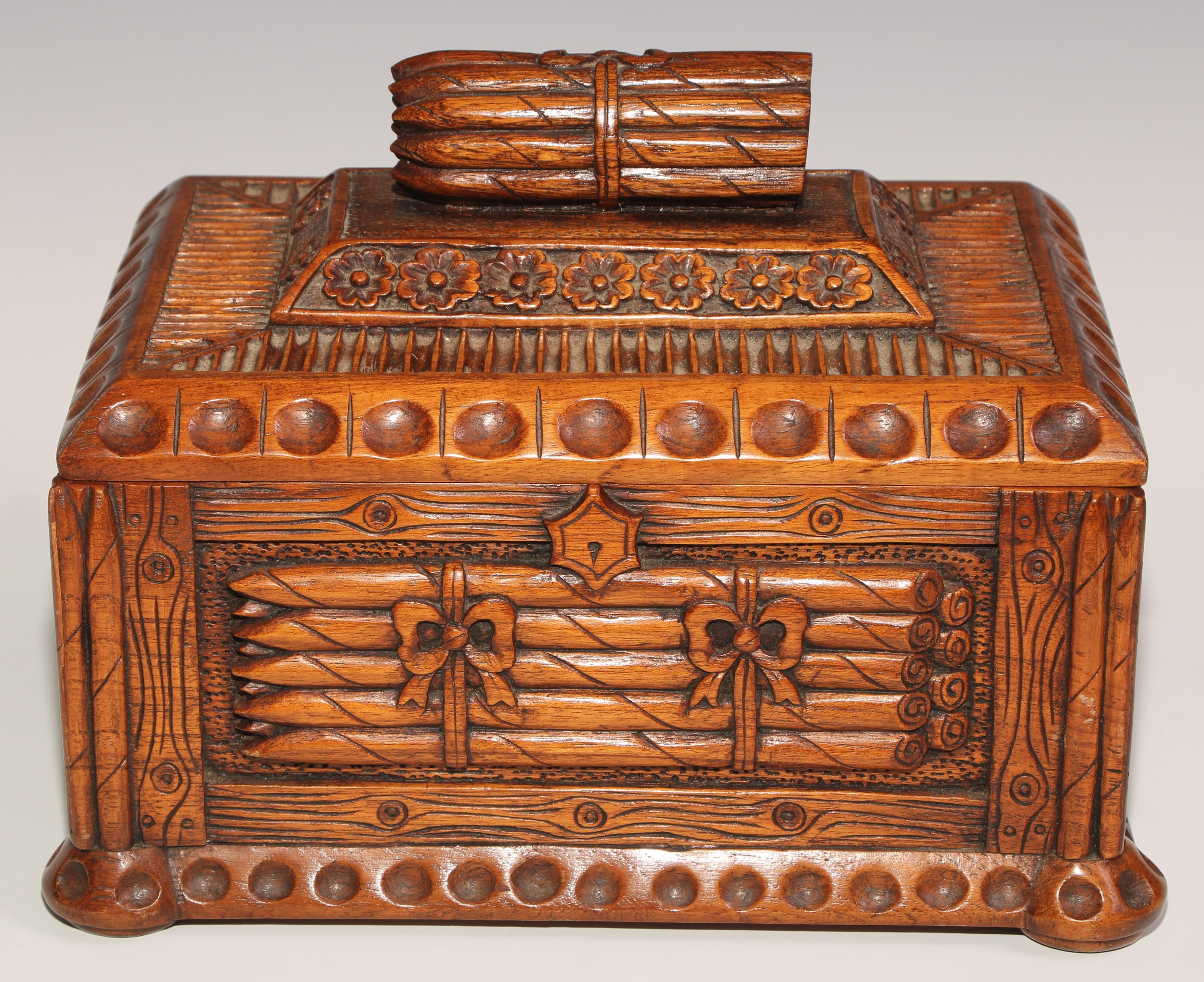 An unusual hardwood rectangular cigar box, carved and surmounted with bundles of cigars, 30cm