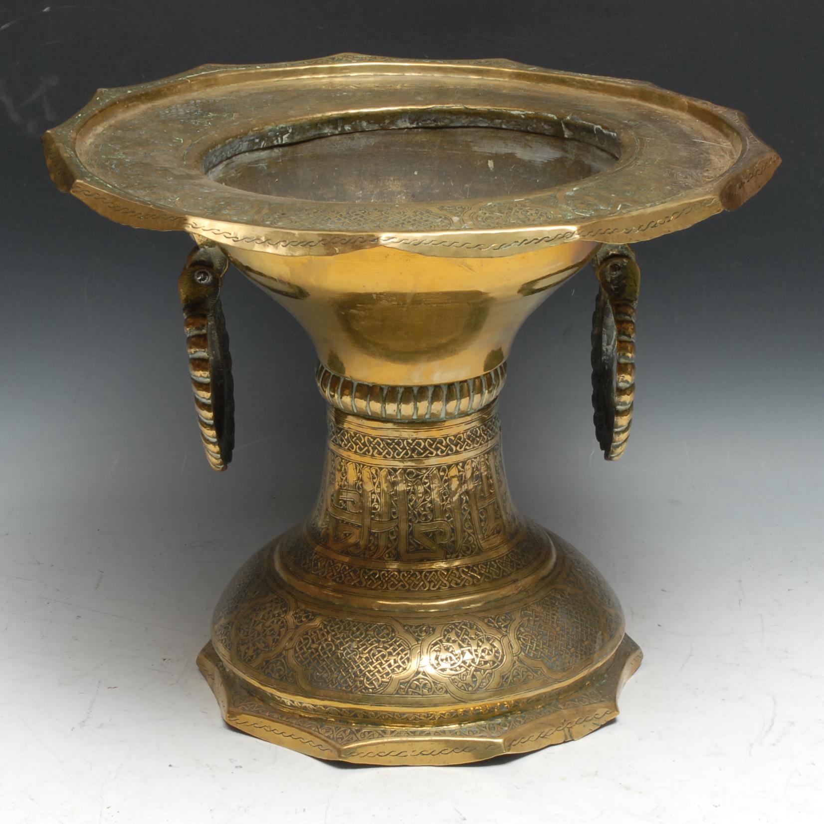 A Middle Eastern brass pedestal brazier, profusely chased in the Islamic taste with Arabic script
