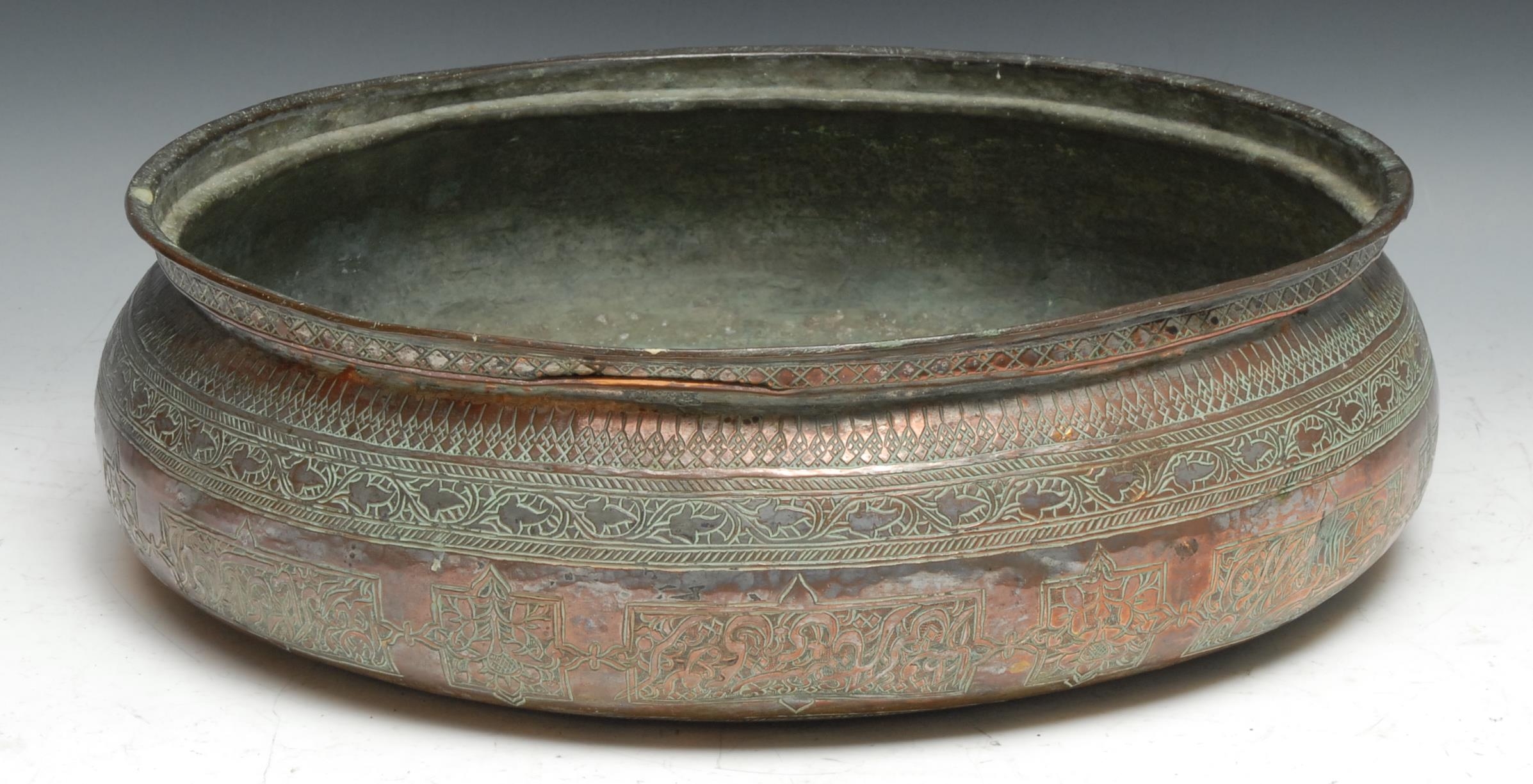 A large Middle Eastern copper bowl chased in the Islamic taste with Arabic calligraphy, scrolling