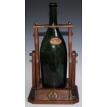 A large French cognac pouring cradle, Remy Martin Cognac, holding a large green vacant bottle,