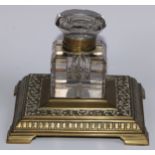 A large Victorian brass square inkstand, cut glass well with hinged cover, cast base with shallow