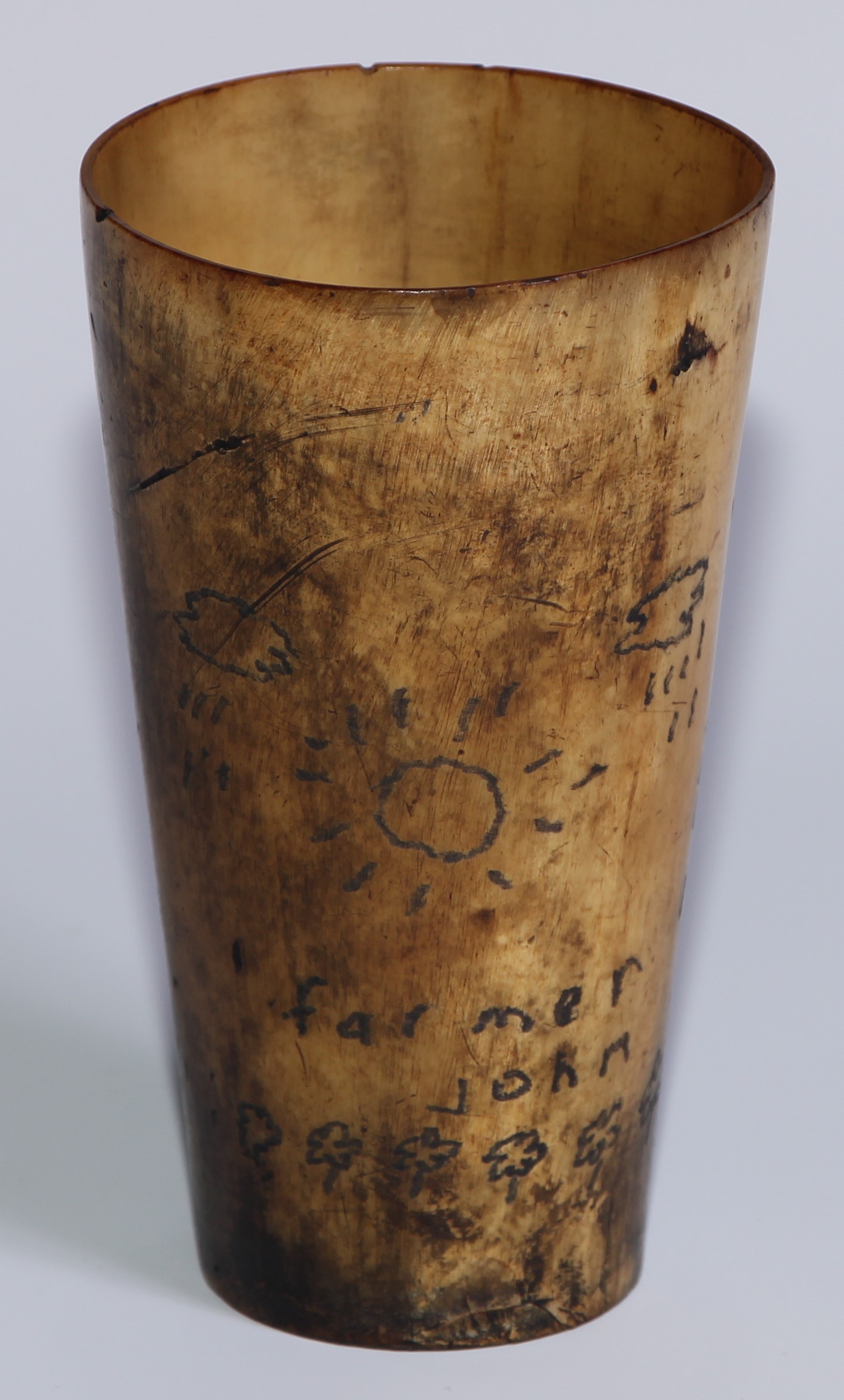 A 19th century tapered cylindrical cattle horn beaker, sgrafitto scrimshaw engraved with sun, rainn,