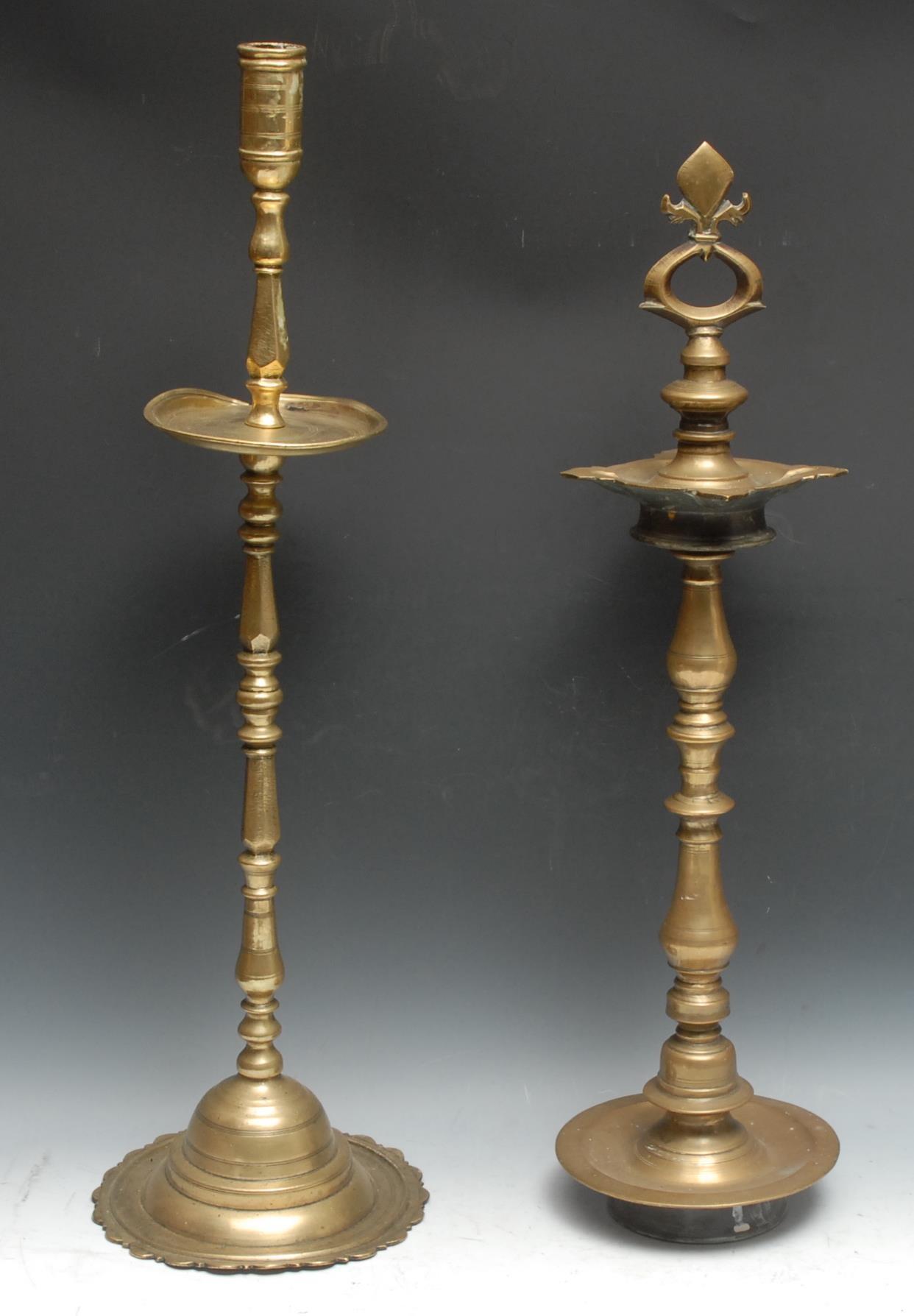A large Indian brass candlestick, cylindrical sconce above a broad drip pan, domed lotus shaped