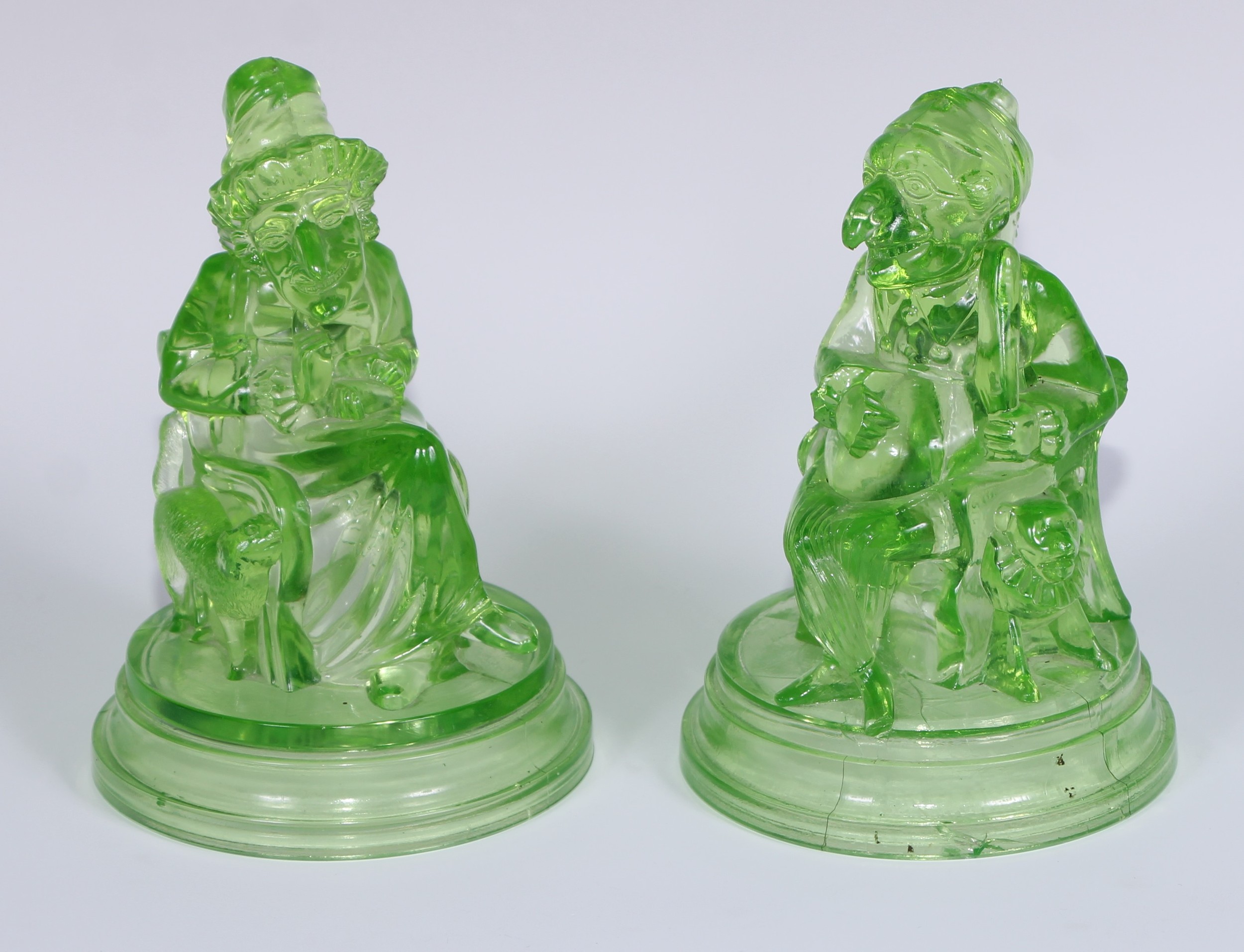 A pair of John Derbyshire press moulded uranium glass models, of Mr Punch and Judy, circular