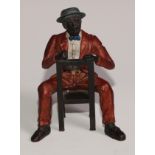 A cold painted bronze, of a Mississippi dandy, finely dressed and seated backwards on a chair,