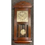 An early 20th century oak cased wall clock, carved cresting, silvered face with Arabic numerals,