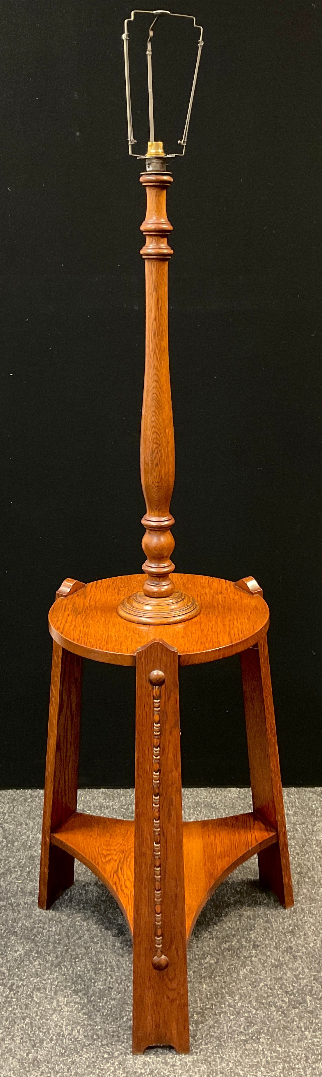 An Arts and Crafts oak table standard-lamp, turned lamp column to top, circular tripod table base,