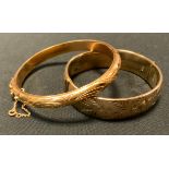 A gold coloured metal hinge bangle, compression clasp, safety chain & buckle, indistinctly marked,