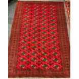 A Turkoman rug / carpet, knotted in rich red, with a multi medallion field, wide stylised