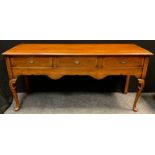 A George III style reproduction cross-banded oak dresser base / sideboard, over-sailing top, three