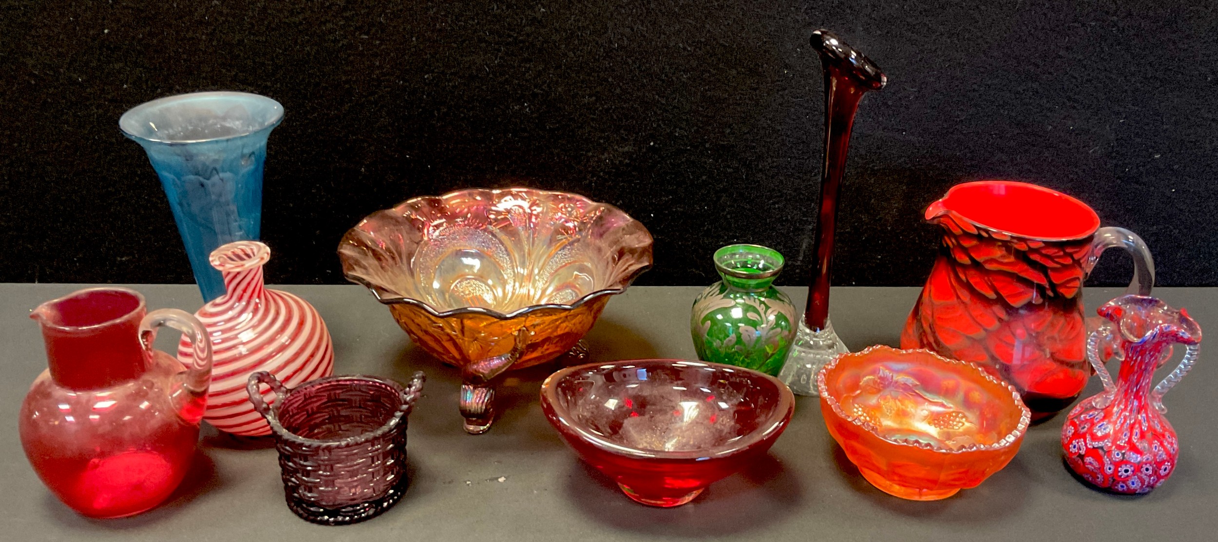 A press moulded carnival glass bowl, dolphin feet, 20.35cm diam; a Victorian cranberry glass jug;