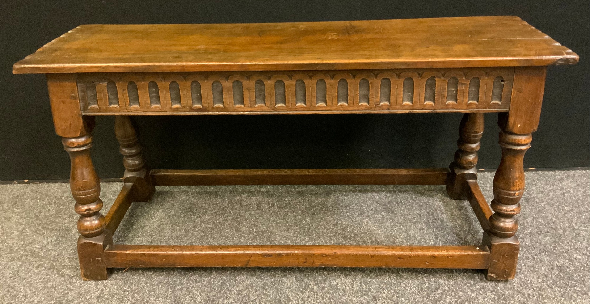 A 19th century oak long stool, rectangular over-sailing top, cut detailing, carved frieze, turned