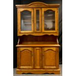 A modern stained beechwood dresser, glazed doors to top, pair of panelled cupboard doors to base,