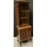 A narrow mahogany book case cabinet, single door glazed top enclosing two shelves, above two door