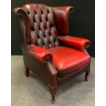 A Chesterfield wing-back armchair, deep button back, sang de bouef red leather, cabriole legs, 102cm