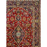 A Kashan rug / carpet, hand-knotted in rich tones of red, cream, indigo, and blue, 202cm x 134cm.